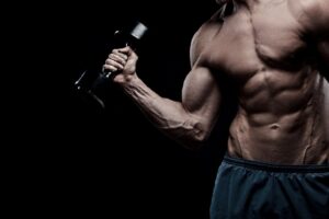 Guy in a very good shape holding the dumbell