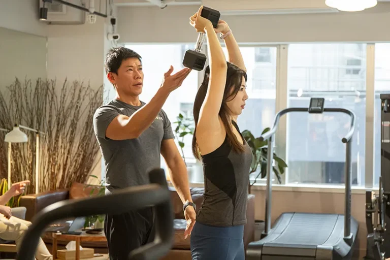 precision personal trainer watching arm workout form in Hong Kong studio