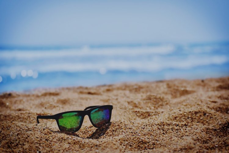 Sunglasses on ground of the beach and sea in the background