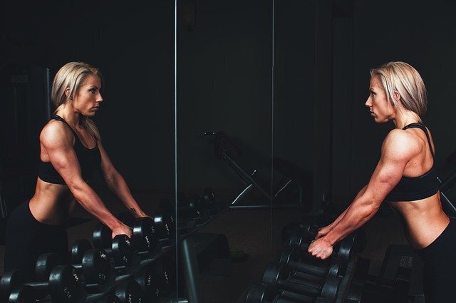 Woman standing in front of the mirror during strenght training and looking at her own reflection