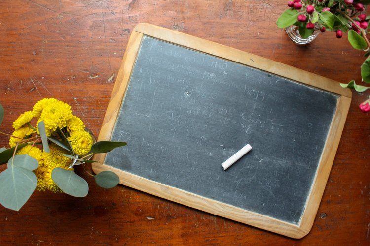 Blackboard with chalk and flowers around
