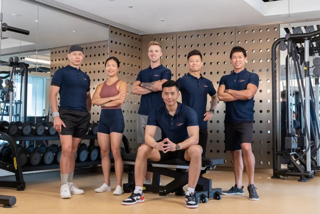 six professional trainers sitting on the ground and smiling at Precision Fitness