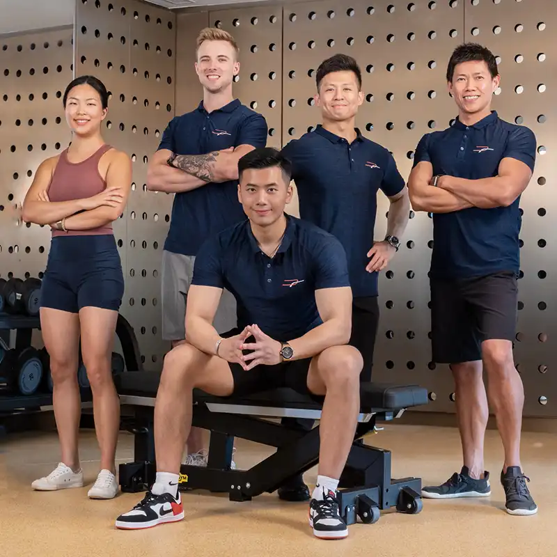six professional trainers sitting on the ground and smiling at Precision Fitness
