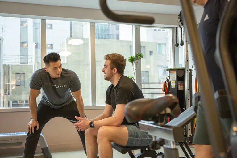 personal trainer coaching a guy on a bench happy