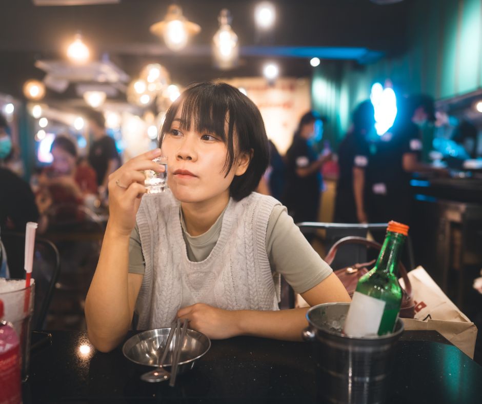 Alcohol Myths. Asian woman at bar drinking looking away